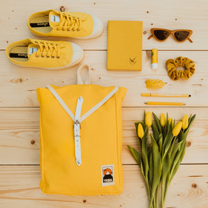 Gelber YKRA Scoutbackpack neben gelben Tulpen und gelben Sneakern