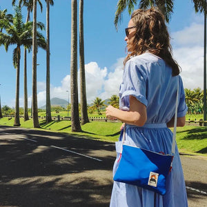 Frau mit blauer Side Pouch läuft im Sommer an Palmen