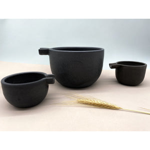 Minimalistischer eleganter Krug und zwei Kännchen schwarze Keramik mit Weizengrashalm auf dem Bild