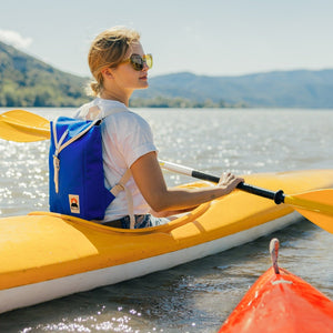 Frau in Kanu auf Wasser mit YKRA Scout Rucksack in blau