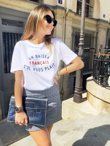 Frau mit Sonnenbrille und Minirock trägt T-Shirt un Baiser français s‘il vous plaît