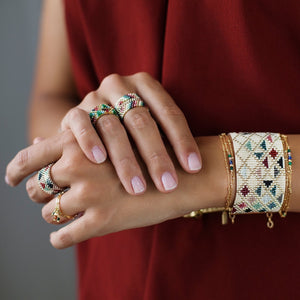 Frau mit lackierten Fingernägeln trägt um ihr linkes Handgelenk handgewebtes Perlenarmband von Marion Mazo 