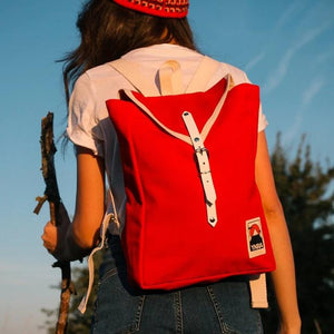 Frau mit Wanderstock und roter Mütze trägt Ykra Scout Rucksack in rot