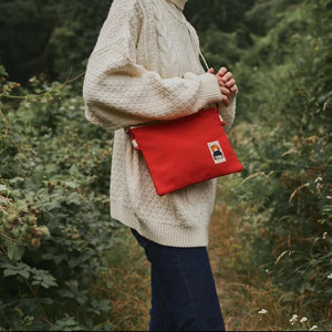Frau mit weißem Wollpullover und roter YKRA Umhängetsche Side Pouch