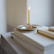 Lade das Bild in den Galerie-Viewer, Bronze Kerzenhalter von Ovo mit brennender dünner Kerze auf silbernen Teller stehend auf gestapelten Büchern
